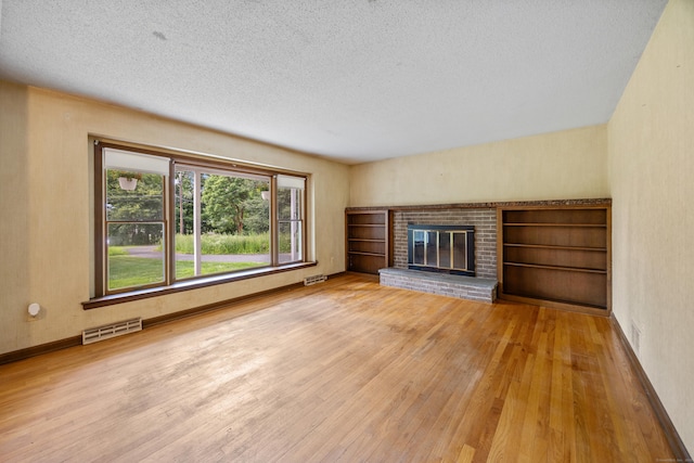 229 Flanders Rd, Southington, CT 06489 - unfurnished living room featuring hardwood / wood-style floors, a textured ceiling, and a fireplace