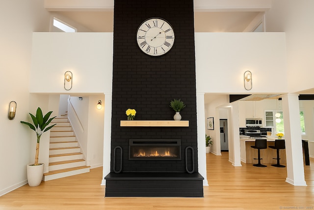 765 Durham Rd, Guilford, CT 06437 - living area with light wood-style floors, a towering ceiling, a fireplace, and stairs