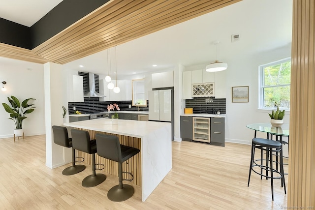 765 Durham Rd, Guilford, CT 06437 - kitchen with wine cooler, freestanding refrigerator, wall chimney exhaust hood, light countertops, and backsplash