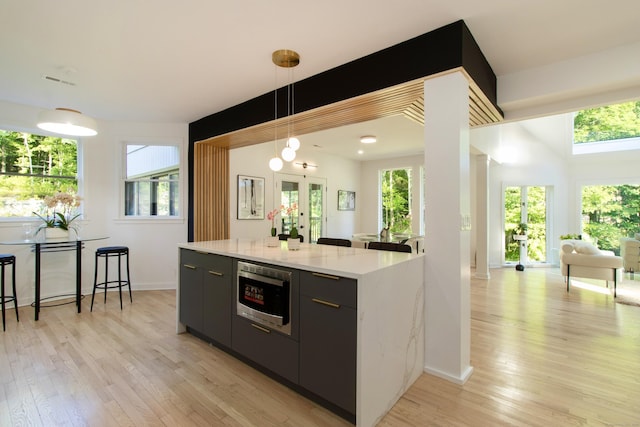 765 Durham Rd, Guilford, CT 06437 - kitchen with stainless steel microwave, light wood-style floors, decorative light fixtures, and a center island
