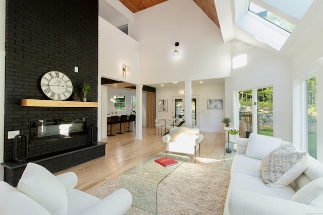 765 Durham Rd, Guilford, CT 06437 - living room featuring high vaulted ceiling, light wood-style flooring, a brick fireplace, and a skylight