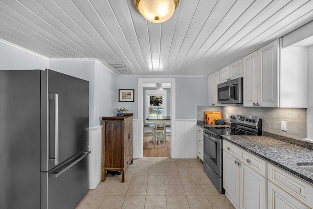 18 Lynde St, Old Saybrook, CT 06475 - kitchen featuring stainless steel appliances, a wainscoted wall, light tile patterned flooring, dark stone counters, and white cabinetry