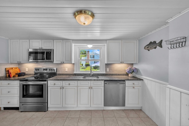 18 Lynde St, Old Saybrook, CT 06475 - kitchen with appliances with stainless steel finishes, a wainscoted wall, light tile patterned floors, dark stone countertops, and decorative backsplash