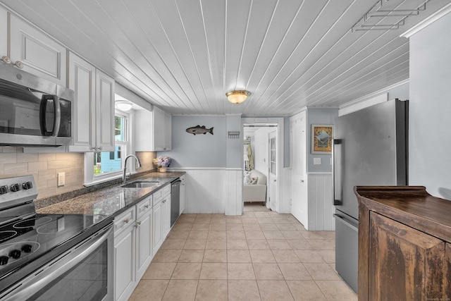 18 Lynde St, Old Saybrook, CT 06475 - kitchen with appliances with stainless steel finishes, white cabinets, a wainscoted wall, dark stone counters, and light tile patterned floors