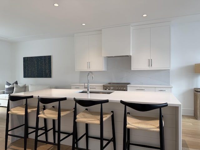 785 Post Rd E Unit 301, Westport, CT 06880 - kitchen featuring light countertops, light wood finished floors, recessed lighting, white cabinetry, and a kitchen bar