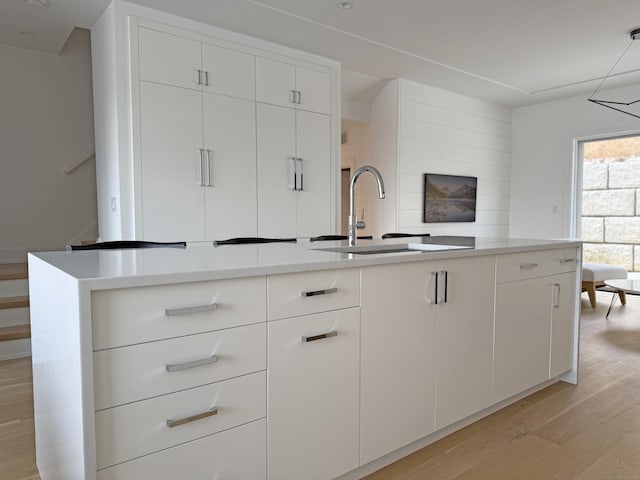 785 Post Rd E Unit 301, Westport, CT 06880 - kitchen with light wood-style floors, white cabinetry, light countertops, and hanging light fixtures