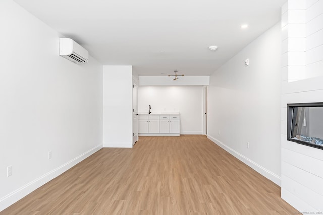 44 Williams St, Stonington, CT 06379 - unfurnished living room with a wall mounted air conditioner, light wood-type flooring, a fireplace, and bar with sink