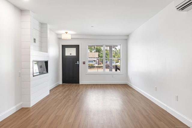 44 Williams St, Stonington, CT 06379 - entrance foyer featuring wood finished floors, a wall mounted air conditioner, and a large fireplace