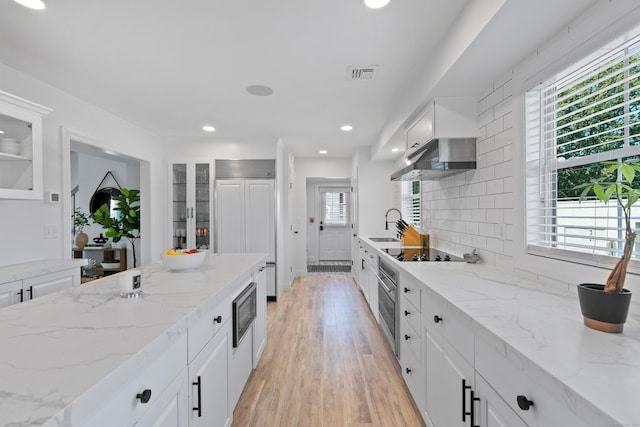 44 Williams St, Stonington, CT 06379 - kitchen featuring stainless steel appliances, recessed lighting, light wood finished floors, exhaust hood, and glass insert cabinets