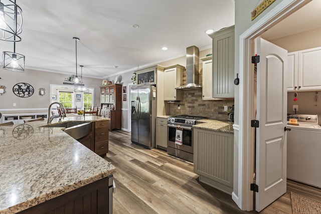 32 Mockingbird Dr Unit 32, Killingly, CT 06239 - kitchen with appliances with stainless steel finishes, wall chimney range hood, washer / clothes dryer, ornamental molding, and wood finished floors