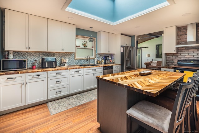 93 Kettletown Woods Rd, Southbury, CT 06488 - kitchen featuring butcher block countertops, stainless steel appliances, wall chimney exhaust hood, light wood-style floors, and a breakfast bar