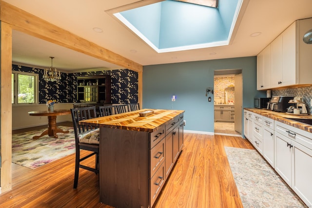 93 Kettletown Woods Rd, Southbury, CT 06488 - kitchen featuring butcher block counters, white cabinets, light wood finished floors, a kitchen bar, and a chandelier