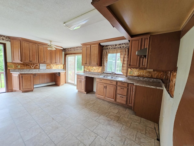 947 Ekonk Hill Rd, Voluntown, CT 06384 - kitchen with decorative backsplash, baseboard heating, a ceiling fan, brown cabinets, and built in desk