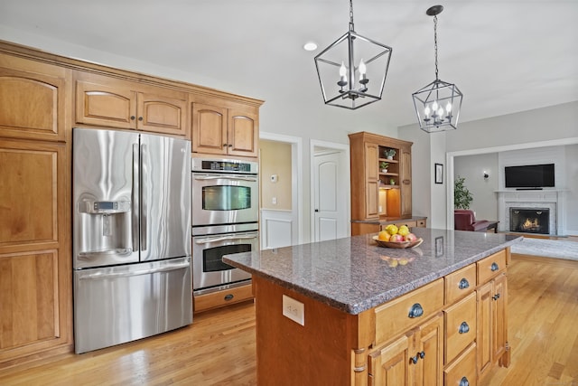 36 Blueberry Ln, Canton, CT 06019 - kitchen with stainless steel appliances, a center island, a chandelier, dark stone countertops, and a lit fireplace