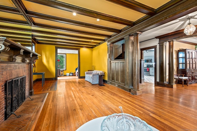 400 Norton Pkwy, New Haven, CT 06511 - unfurnished living room with ornate columns, crown molding, hardwood / wood-style flooring, a brick fireplace, and beamed ceiling