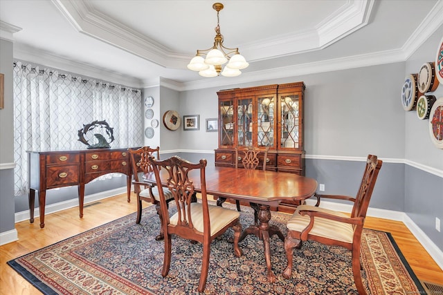 24 Windflower Ln, Shelton, CT 06484 - dining area featuring a chandelier, light wood-style flooring, a raised ceiling, and ornamental molding