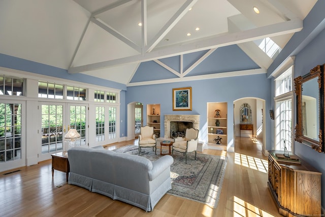 370 Northrop St, Bridgewater, CT 06752 - living area featuring high vaulted ceiling, arched walkways, a premium fireplace, beam ceiling, and plenty of natural light