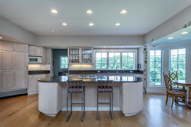 370 Northrop St, Bridgewater, CT 06752 - kitchen featuring recessed lighting, a center island, white microwave, glass insert cabinets, and a breakfast bar area