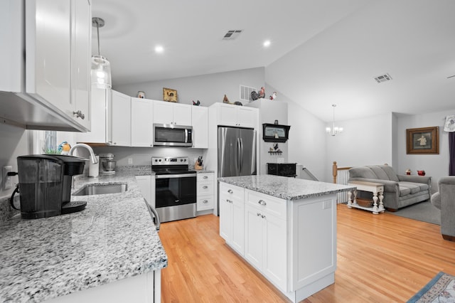 233 W Rd, East Haddam, CT 06420 - kitchen with stainless steel appliances, vaulted ceiling, a center island, light wood-style floors, and white cabinets