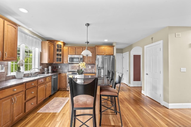 31 Crimson Hts, Portland, CT 06480 - kitchen featuring appliances with stainless steel finishes, light wood finished floors, a kitchen breakfast bar, glass insert cabinets, and arched walkways