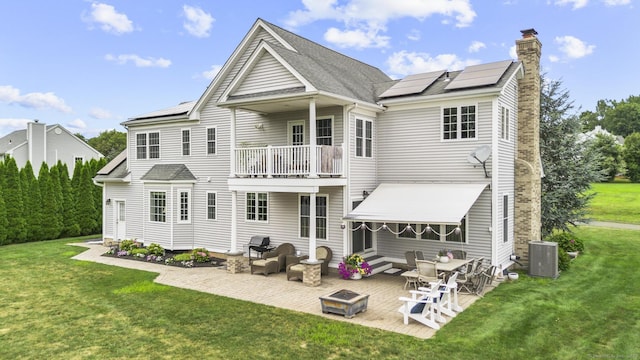 31 Crimson Hts, Portland, CT 06480 - rear view of house with a balcony, solar panels, a patio area, a lawn, and a chimney