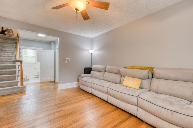 6 Rau Street Ext, Vernon, CT 06066 - living area featuring stairs, light wood-style floors, a textured ceiling, a baseboard heating unit, and ceiling fan