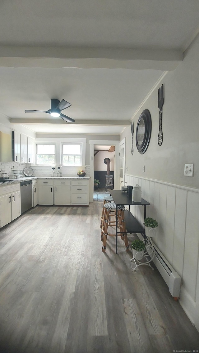 62 Park St, Stafford, CT 06076 - kitchen featuring stainless steel dishwasher, a wood stove, wood finished floors, wainscoting, and a ceiling fan