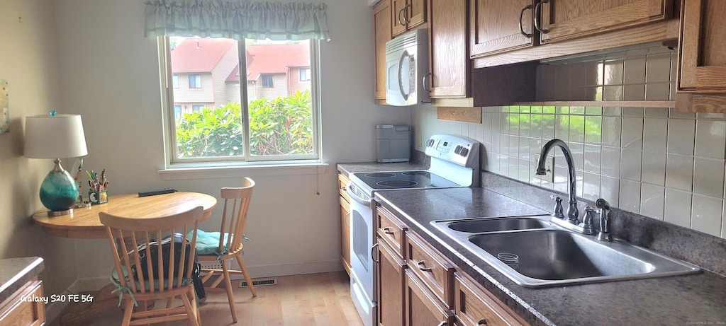 108 Greenwoods Ln Unit 108, East Windsor, CT 06088 - kitchen with white appliances, dark countertops, decorative backsplash, light wood-type flooring, and brown cabinetry
