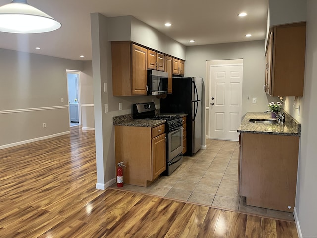 2955 Madison Ave Apt 40, Bridgeport, CT 06606 - kitchen with stainless steel appliances, light wood-style floors, recessed lighting, dark stone counters, and brown cabinets