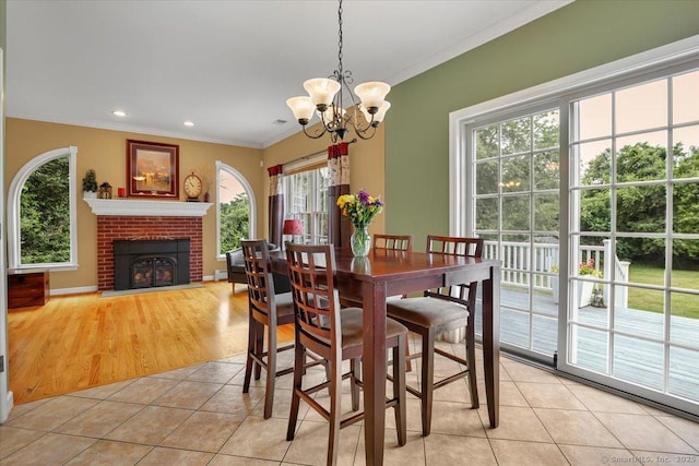 2 Kimberly Way, Marlborough, CT 06447 - dining area with healthy amount of natural light, a chandelier, ornamental molding, light tile patterned floors, and a brick fireplace