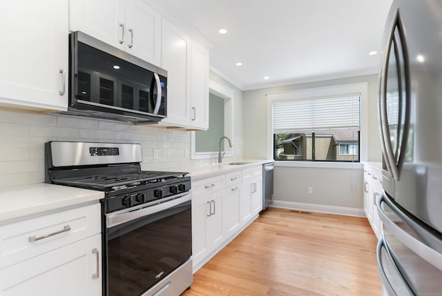 194 Bayfield Ln Unit A, Stratford, CT 06614 - kitchen featuring appliances with stainless steel finishes, light wood-style floors, light countertops, white cabinetry, and backsplash