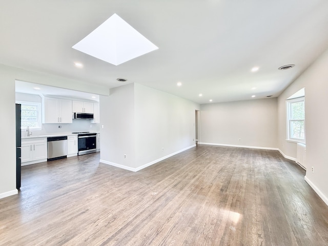 10 Meadowpark Ave W, Stamford, CT 06905 - unfurnished living room featuring light wood finished floors, a skylight, recessed lighting, and radiator