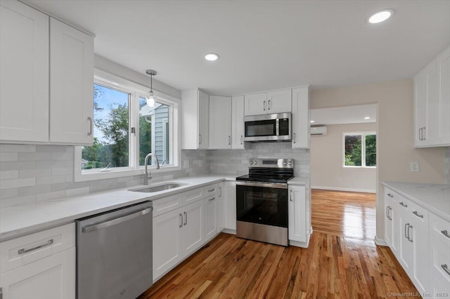219 Browning Rd, Norwich, CT 06360 - kitchen featuring stainless steel appliances, white cabinetry, wood finished floors, decorative backsplash, and plenty of natural light