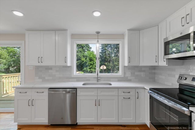 219 Browning Rd, Norwich, CT 06360 - kitchen with appliances with stainless steel finishes, white cabinets, light stone countertops, backsplash, and recessed lighting