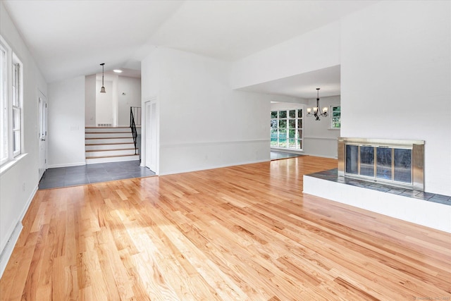 195 Whittier Rd, New Haven, CT 06515 - unfurnished living room with wood finished floors, stairs, a chandelier, vaulted ceiling, and a tile fireplace