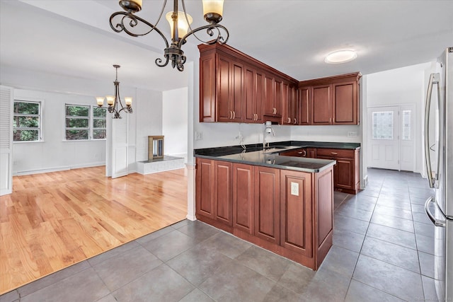 195 Whittier Rd, New Haven, CT 06515 - kitchen featuring a chandelier, dark countertops, freestanding refrigerator, light tile patterned floors, and a peninsula