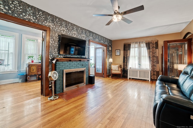 135 Park Ter, Waterbury, CT 06708 - living room featuring radiator, ceiling fan, a brick fireplace, wood finished floors, and wallpapered walls