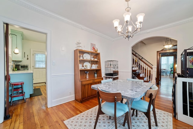 135 Park Ter, Waterbury, CT 06708 - dining area with arched walkways, crown molding, light wood finished floors, a chandelier, and stairway