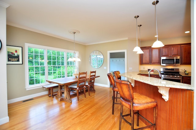 190 Shadow Pond, Suffield, CT 06078 - kitchen with stainless steel appliances, crown molding, a breakfast bar area, light wood finished floors, and light stone countertops