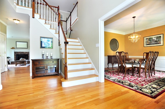 190 Shadow Pond, Suffield, CT 06078 - dining space featuring wood finished floors, ornamental molding, stairs, a chandelier, and a fireplace