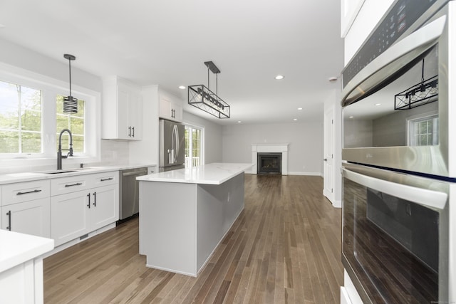 61 N Woods Rd, Hamden, CT 06518 - kitchen with appliances with stainless steel finishes, a fireplace, open floor plan, white cabinets, and recessed lighting