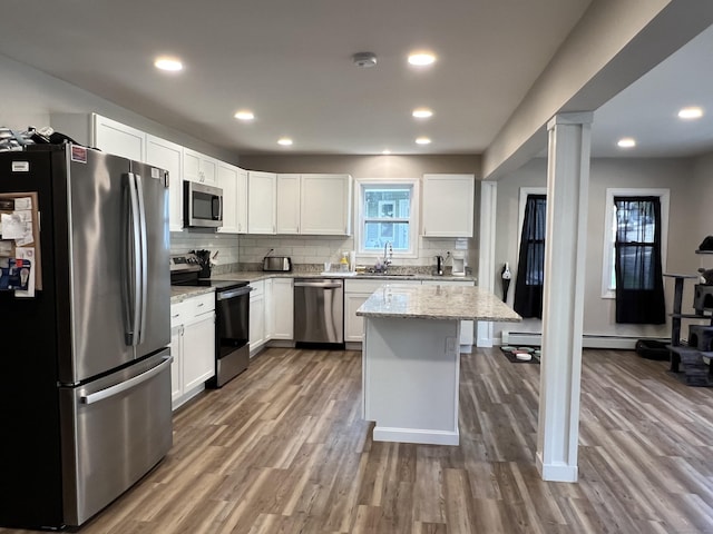 34 Division St, Norwich, CT 06360 - kitchen featuring appliances with stainless steel finishes, light stone counters, wood finished floors, decorative backsplash, and white cabinetry