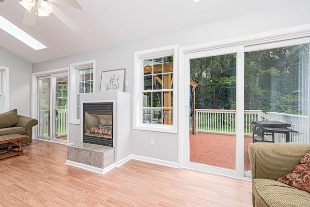 93 Cook Hill Rd, Killingly, CT 06239 - living room featuring a ceiling fan, vaulted ceiling, light wood-style flooring, a glass covered fireplace, and a skylight