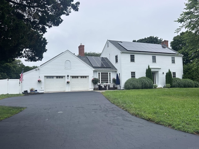8 Sharon Ln, Old Saybrook, CT 06475 - view of front facade featuring a chimney, solar panels, asphalt driveway, and an attached garage
