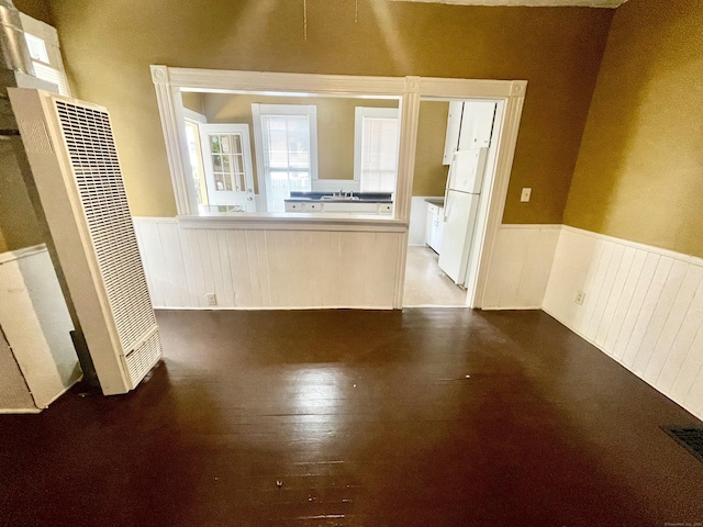 271 S Main St, Torrington, CT 06790 - unfurnished living room featuring a heating unit, wainscoting, and wood-type flooring