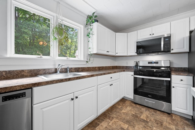 20 Harris St, Enfield, CT 06082 - kitchen featuring appliances with stainless steel finishes, dark countertops, stone finish floors, and white cabinetry