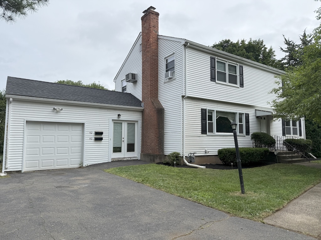 40 Newton St, Berlin, CT 06037 - colonial inspired home with a chimney, an attached garage, a front yard, driveway, and french doors