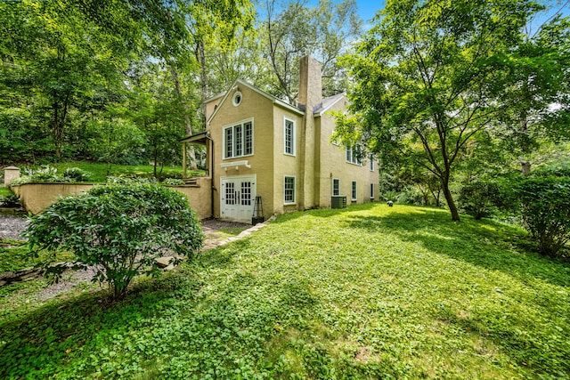 48 Own Home Ave, Wilton, CT 06897 - rear view of house with stucco siding, french doors, an attached garage, a chimney, and a yard