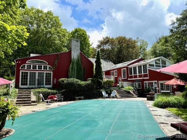 4 Whippoorwill Ln, Weston, CT 06883 - rear view of house with stairs, a covered pool, and a chimney