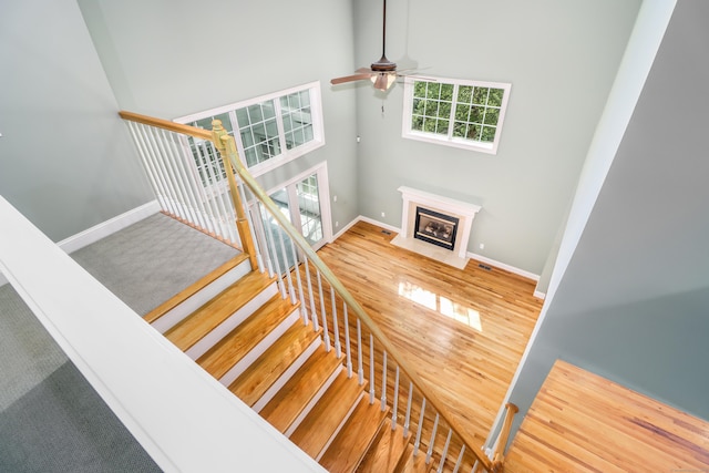 21 Great Heron Ln Unit 21, Brookfield, CT 06804 - staircase featuring a towering ceiling, a ceiling fan, wood finished floors, and a fireplace with flush hearth